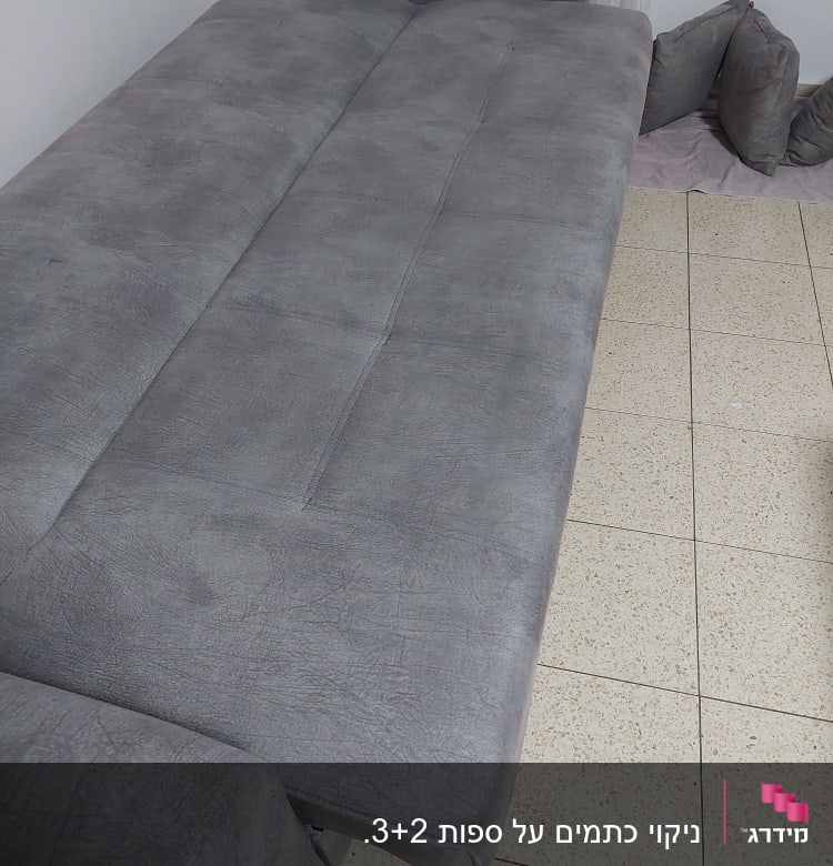 ספה אפורה על רצפת אריחים, כריות בצד